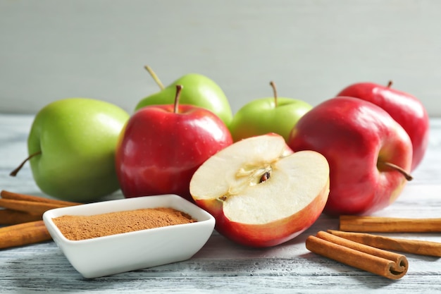 Composition with fresh apples and cinnamon sticks on wooden table