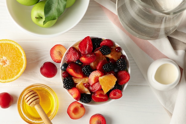 Composition with fresh fruit salad on white wooden table