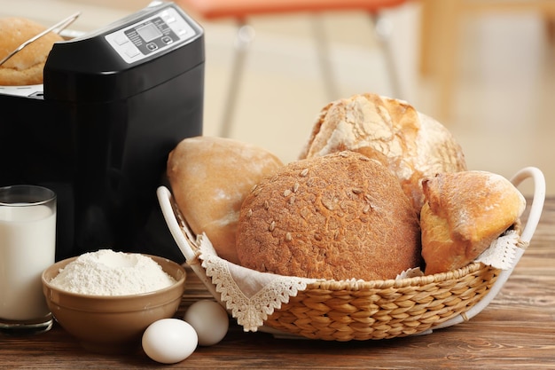 Composition with fresh loaves bread machine and ingredients on table