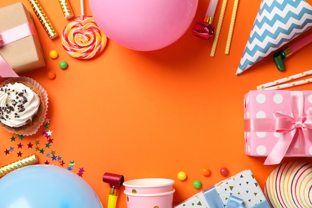 Composition with gift boxes and b-day accessories on orange background, space for text