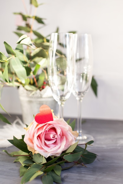 Composition with glass for champagne. Flowers and hearts on grey concrete background.
