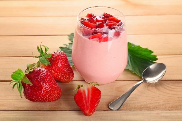 Composition with glass of fresh homemade yogurt and strawberries on wooden background