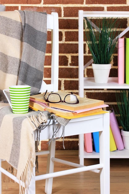 Photo composition with glasses and books on chair on cabinet and wall background