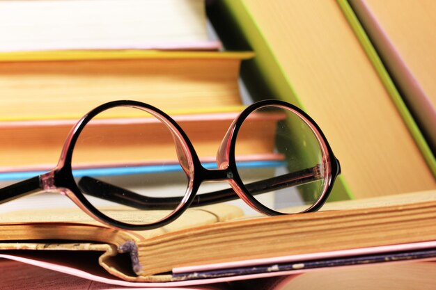 Photo composition with glasses and books on table on light background