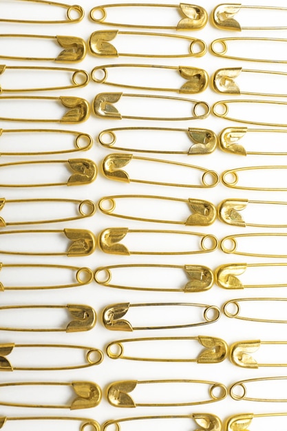 Composition with golden safety pins on white background