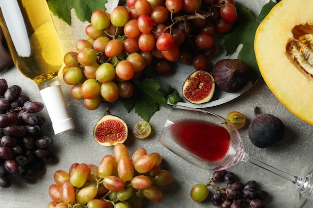 Composizione con uva, vino, fichi e melone su grigio