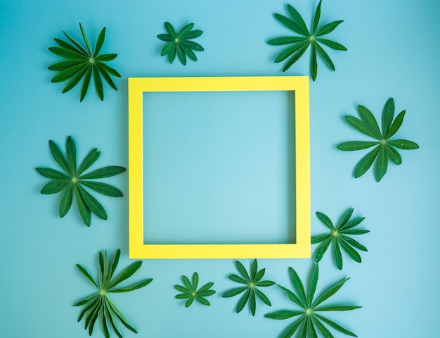 Composition with green leaves and empty yellow frame Creative layout of nature copy space