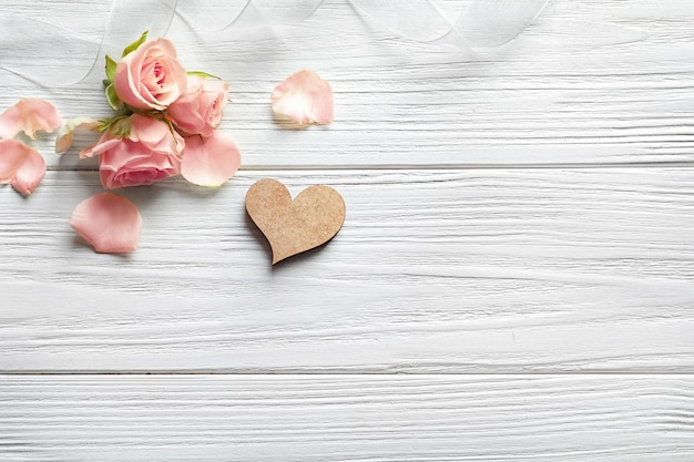 Composition with heart and beautiful flowers on white wooden background