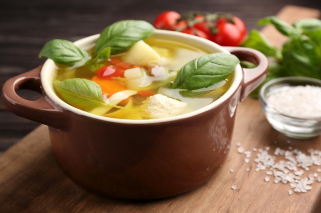 Photo composition with homemade turkey soup in casserole on wooden table