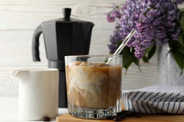 Composition with ice coffee and flowers on white wooden