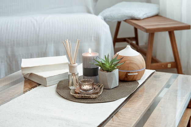 Composition with incense sticks, diffuser, candles and books on the table in the interior of the room.