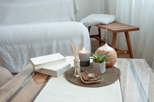 Composition with incense sticks, diffuser, candles and books on the table in the interior of the room.