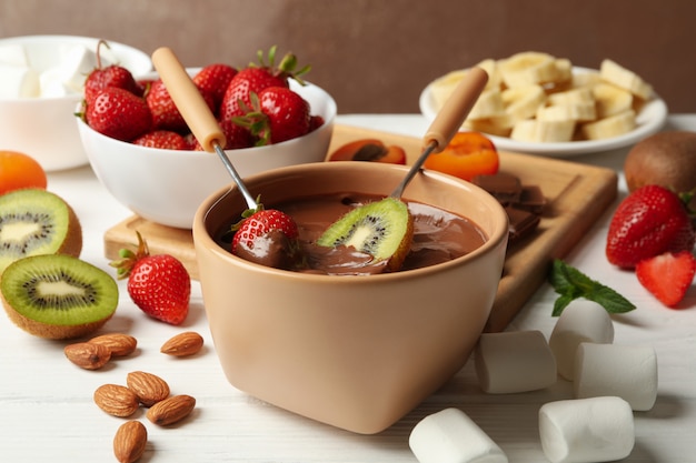 Composition with ingredients for chocolate fondue on white wooden background. Cooking fondue