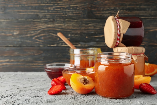 Photo composition with jam and ingredients on gray table, space for text