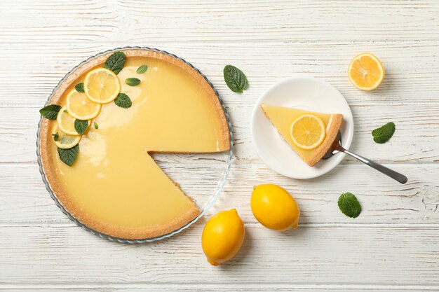 Composition with lemon tart on white wooden background, top view