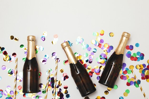 Composition with mini champagne bottles and glitter on white space, copy space