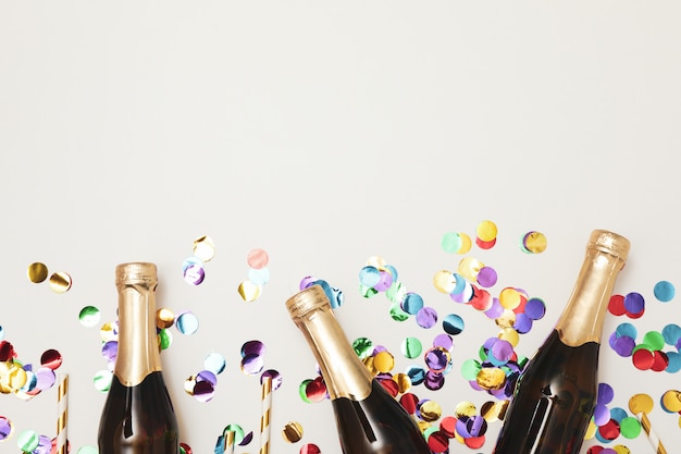 Composition with mini champagne bottles and glitter on white space, copy space