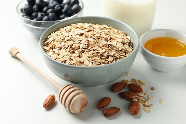 Composition with oatmeal flakes on white wall, close up. Cooking breakfast