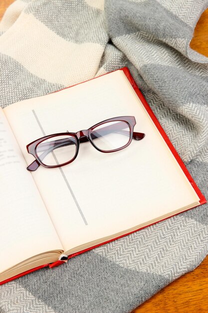 Photo composition with old book eye glasses and plaid on wooden background