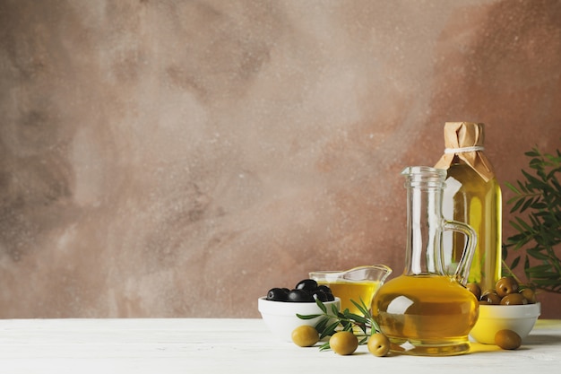 Фото Композиция с оливковым маслом и оливками против коричневого, место для текста