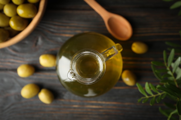 Photo composition with olive oil and olives on wooden, top view