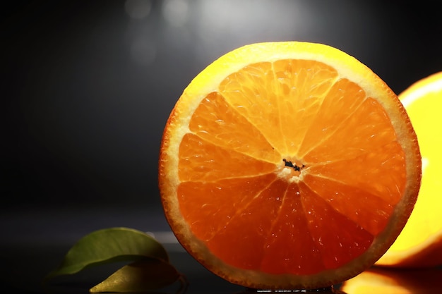 Composition with orange and grapefruit slices on a black
background a slice of orange with back light on a black background
with water drops juicy orange on a table