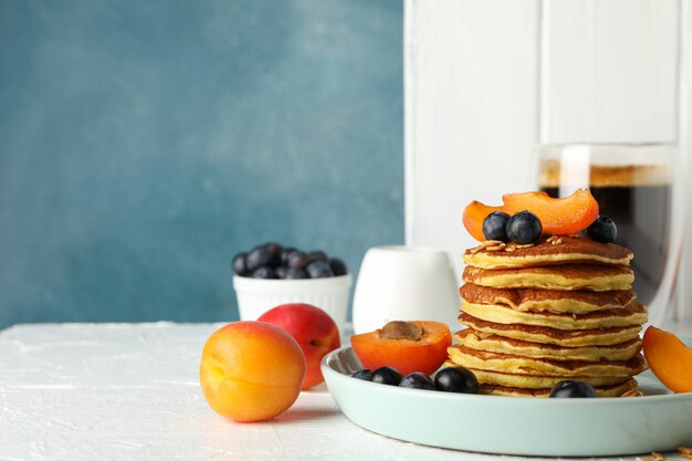 Composizione con i pancake e la frutta sulla tavola bianca. colazione dolce