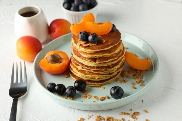 Composition with pancakes and fruits on white table. Sweet breakfast