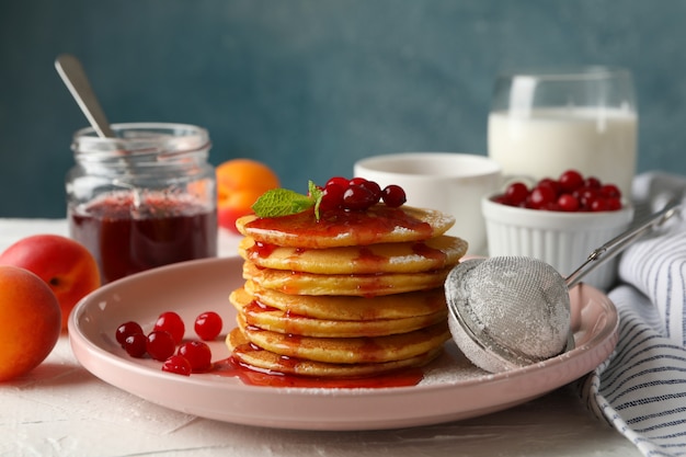 Composition with pancakes with jam and cranberry on white table