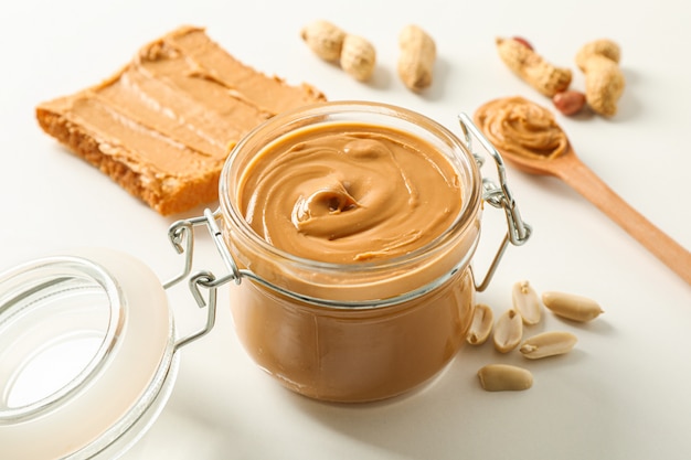 Photo composition with peanut butter sandwich, glass jar, peanut and spoon