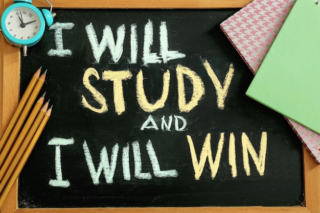 Composition with phrase I will study and I will win and stationery on chalkboard top view