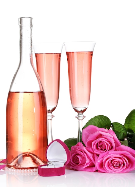 グラス、ボトル、ピンクのバラにピンクのスパークリングワインを白で分離したコンポジション