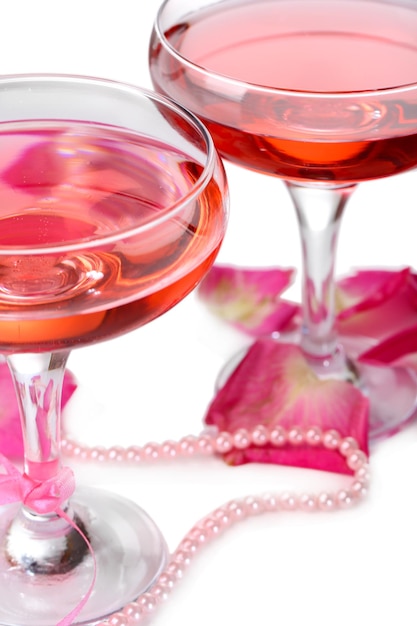 Composition with pink sparkle wine in glasses and rose petals isolated on white