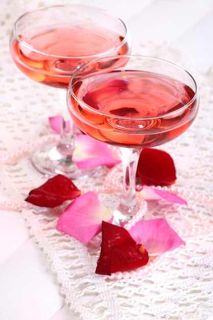 Composition with pink sparkle wine in glasses and rose petals isolated on white