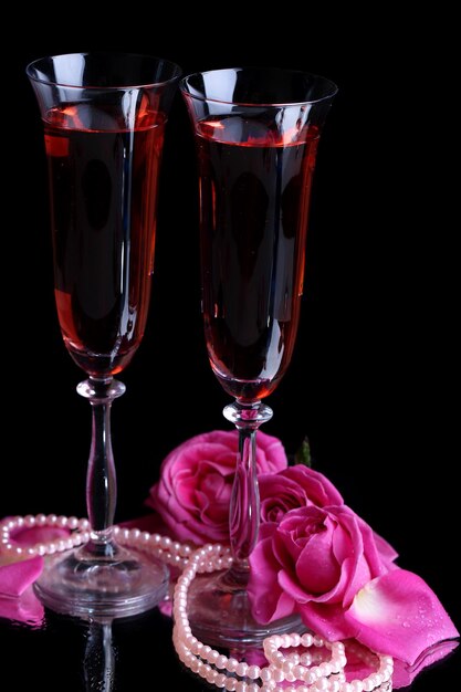 Composition with pink  wine in glasses and  roses isolated on black