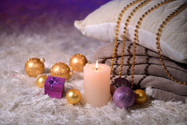 Композиция с пледами, свечами и рождественскими украшениями, на белом ковре на ярком фоне