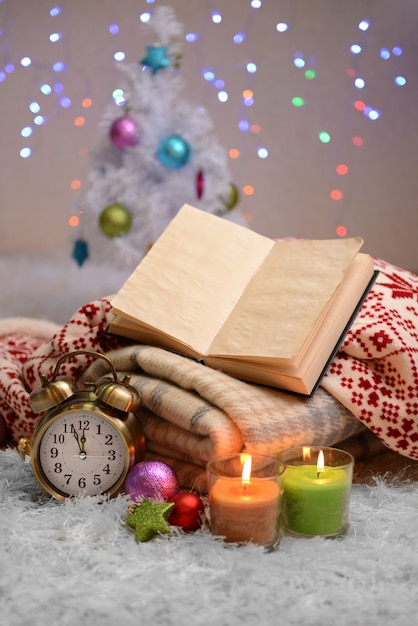 Composition with plaids, candles and Christmas decorations, on white carpet on bright wall