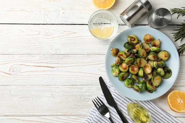 Composition with plate of brussels sprout on wooden background, top view