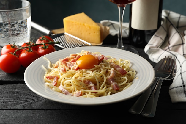 Composition with plate of tasty pasta and wine on wooden wall