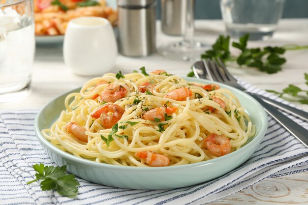 Composition with plate of tasty pasta with shrimps on wooden wall