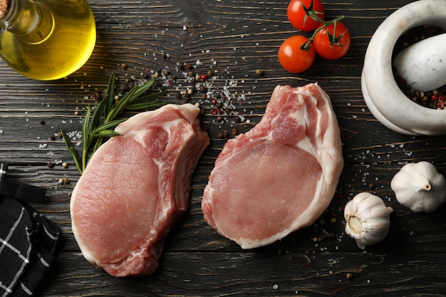 Composition with raw meat for steak and ingredients on wooden background