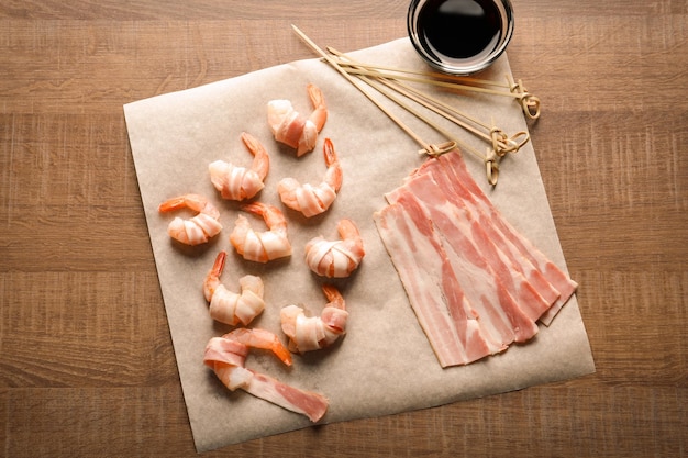 Composition with raw shrimps and bacon on table