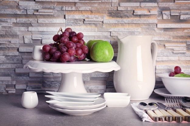 Composition with rustic dinnerware and fruits on light brick background