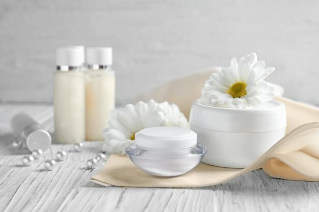 Composition with skin care products and chamomile flowers on wooden table