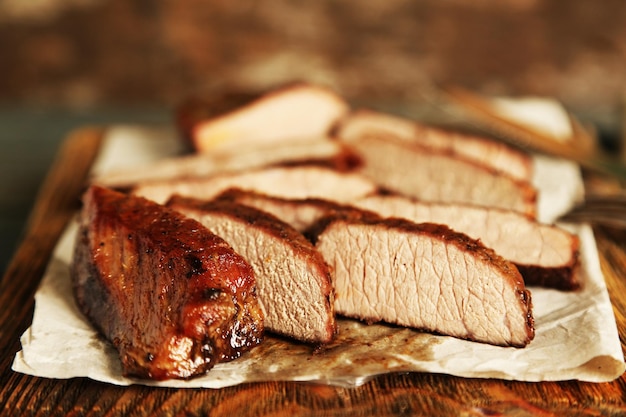 Composition with sliced roasted meat on cutting board on wooden background