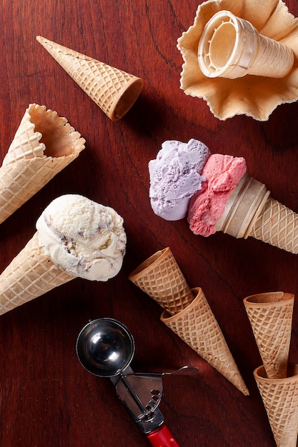 Composition with strawberry, grape and vanilla ice cream in waffle cone on wooden background. Copy space. Top view