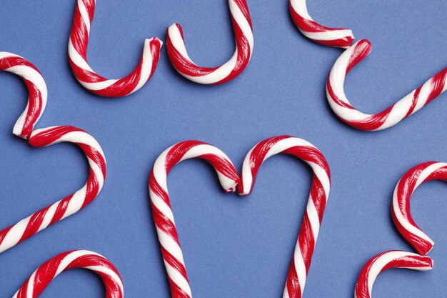 Composition with sweet candy canes on color background. Space for text.