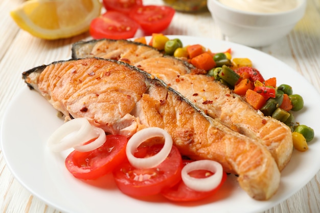 Composition with tasty grilled salmon on wooden table, close up