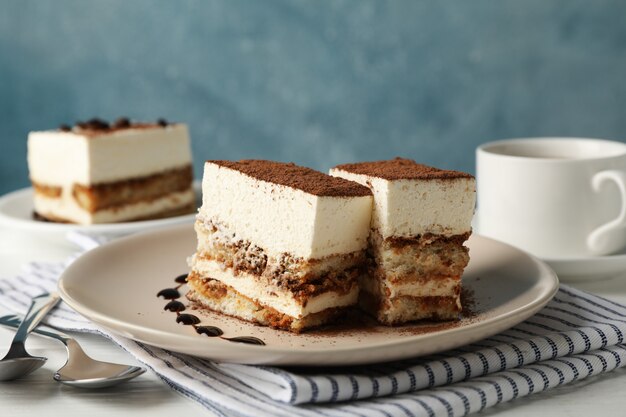 Composition with tasty tiramisu and cocoa drink on white wooden table. Delicious dessert