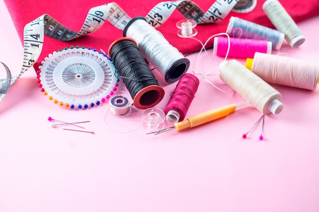 Composition with threads and sewing accessories on pink background